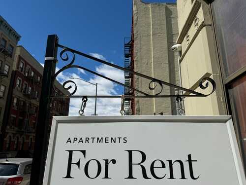 Sign indicating apartments available for rent against a blue sky