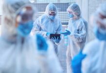 Healthcare professionals in protective gear discussing on a tablet
