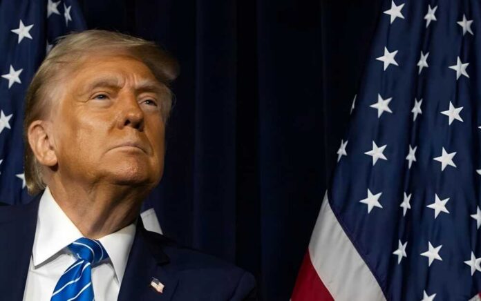 A political figure looking upward beside an American flag