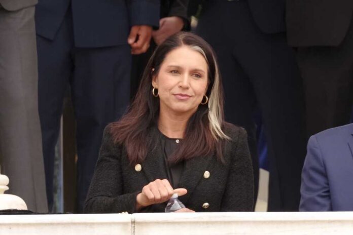 A woman in a black blazer sitting outdoors, holding a water bottle