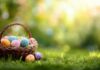 A wicker basket filled with colorful Easter eggs on green grass