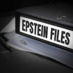 A black binder labeled 'Epstein Files' with papers and a pen beside it