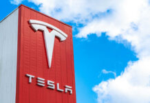 Tesla Scandal: Misleading Self-Driving Claims Exposed Tesla logo on a red corporate sign against a blue sky with clouds