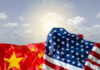 Crumpled flags of the United States and China against a cloudy sky