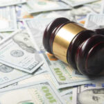 A gavel resting on a pile of hundred dollar bills
