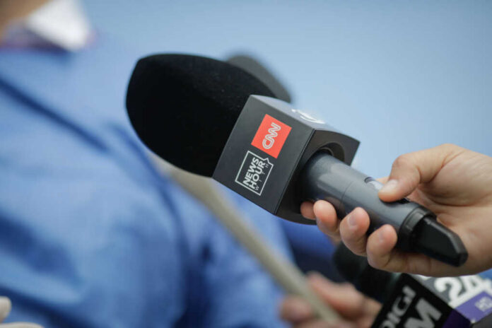 A hand holding a CNN microphone during a news interview