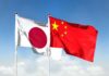 Flags of Japan and China waving against a blue sky