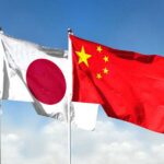 Flags of Japan and China waving against a blue sky