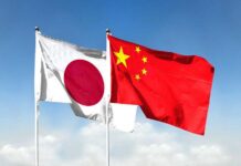 Flags of Japan and China waving against a blue sky