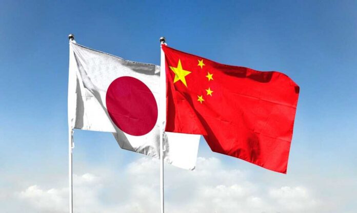 Flags of Japan and China waving against a blue sky
