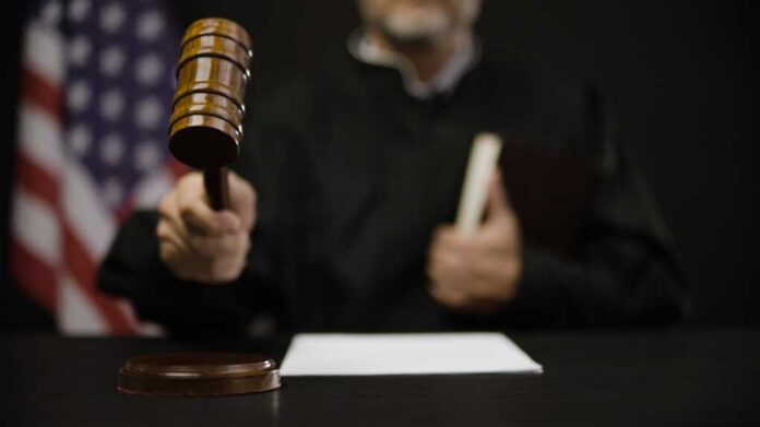 Male,Judge,Hitting,Gavel,,Calling,Court,Members,To,Stand,,United A judge holding a gavel in a courtroom setting