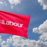 Red flag with 'Labour' logo waving against a cloudy sky