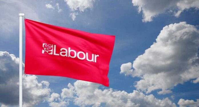 Red flag with 'Labour' logo waving against a cloudy sky