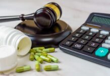 A gavel, medication capsules, and a calculator on a table
