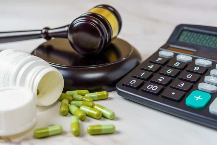 A gavel, medication capsules, and a calculator on a table