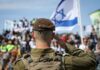 Gaza Flotilla Drama: Aid Mission Disrupted Soldier saluting in front of a crowd with the Israeli flag in the background