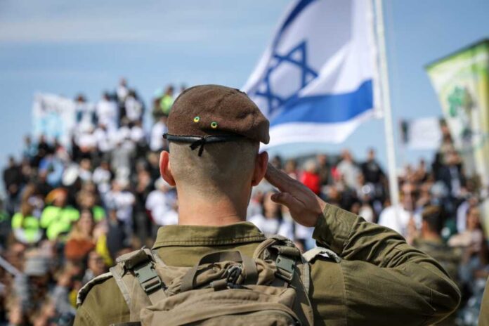 A,Proud,Israeli,Soldier,With,The,Flag Soldier saluting in front of a crowd with the Israeli flag in the background