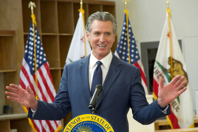 shutterstock_2567671133 California governor speaking at a podium with flags in the background