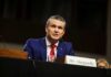 Man in a blue suit speaking at a government hearing