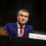 Man in a blue suit speaking at a government hearing
