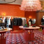 A stylish clothing store interior featuring racks of apparel and decorative tables