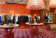 A stylish clothing store interior featuring racks of apparel and decorative tables