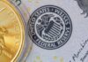 Close-up of a gold coin next to a US dollar bill