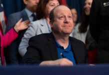 Democrats ATTACK Own Governor Over Election Mercy A government official seated at a table during a signing ceremony