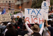 Wealthy Rebels Push for New Tax Revolution Crowd of protesters holding signs advocating for tax reform