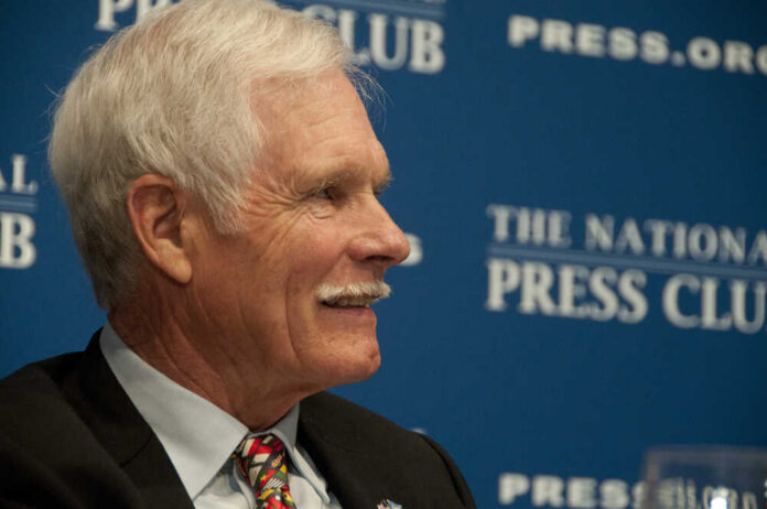 A man with gray hair and a mustache smiling during a press conference