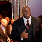 A man in a suit giving a thumbs up at a red carpet event
