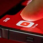 YouTuber Charged in Double Death Case Finger tapping YouTube app icon on smartphone screen