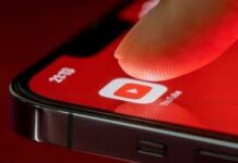 Finger tapping YouTube app icon on smartphone screen