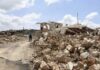Southern Lebanon Pays The Price Again Person walking past rubble and destroyed buildings on a dirt road