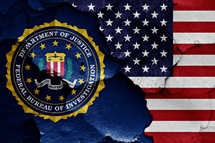 shutterstock1023380488jpg FBI emblem partially obscured by a cracked wall with an American flag background