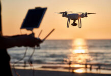 Spy Allegations Await Public Evidence Test A drone flying over a beach at sunset with a person controlling it