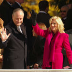 High Bail, Zero Details—What’s Being Hidden? Two public figures waving at an outdoor event surrounded by a crowd
