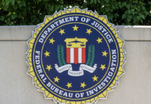 FBI Nabs First ‘Most Wanted’ Fraudster FBI seal featuring the Department of Justice emblem on a wall