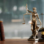 Court Draws Hard Line Around Fed A bronze statue of Lady Justice holding scales and a sword, with law books and a gavel in the foreground
