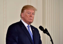 Iran’s ‘Win’ Or Trap For Trump? A political figure standing at a microphone with a serious expression