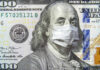 A hundred dollar bill featuring Benjamin Franklin wearing a face mask