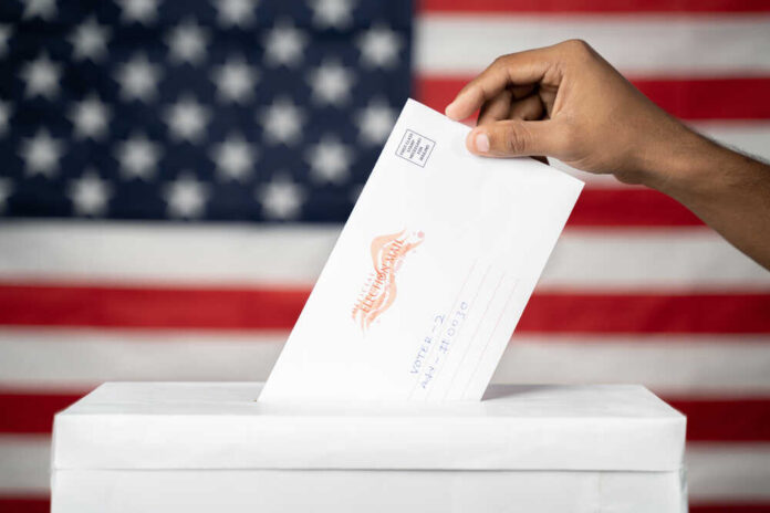 Maski,,India,14,September,,2020,:,Concept,Of,Mail,In A hand placing a ballot into a voting box with an American flag background