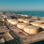 Aerial view of large oil storage tanks near a coastal area