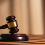 A wooden gavel resting on a circular base with soft lighting