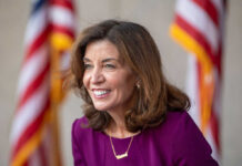 Smiling woman in a purple outfit with American flags in the background