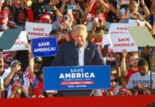 GOP Civil War Erupts Over Voting Crackdown Donald Trump speaking at a political rally with supporters holding signs