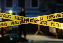Wrong Order Erupts Into Knife Chaos Police tape marking a crime scene with blurred figures in the background