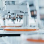 Automated laboratory equipment with robotic arms dispensing liquids into petri dishes