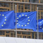Trump Wins Major EU Trade Deal Three European Union flags waving in front of a building
