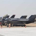 F-35 military jets parked on an airfield with crew members nearby